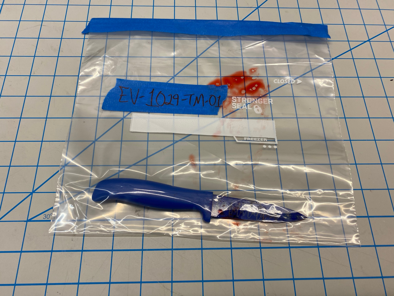 Photo of an evidence bag, which contains the knife used to kill the victim. The knife is blue and has "falalalala" written on the blade.