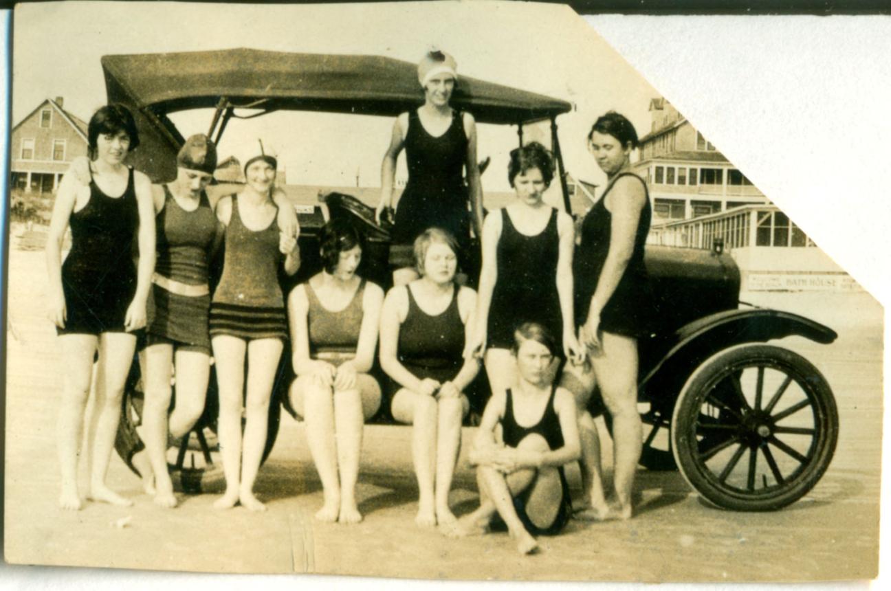 women in swimwear leaning against car at the beach 1920s or 1930s