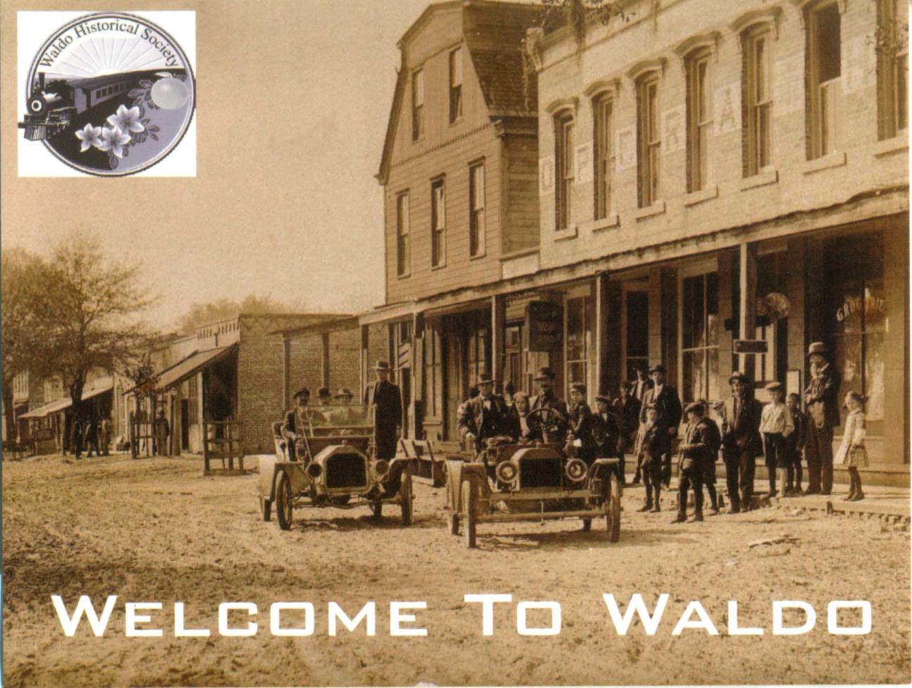 Welcome to Waldo postcard of cars, people, and buildings in 1910