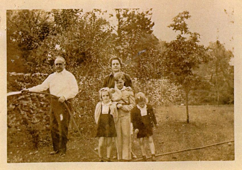 Merchant family, man watering bushes and mother with 3 children