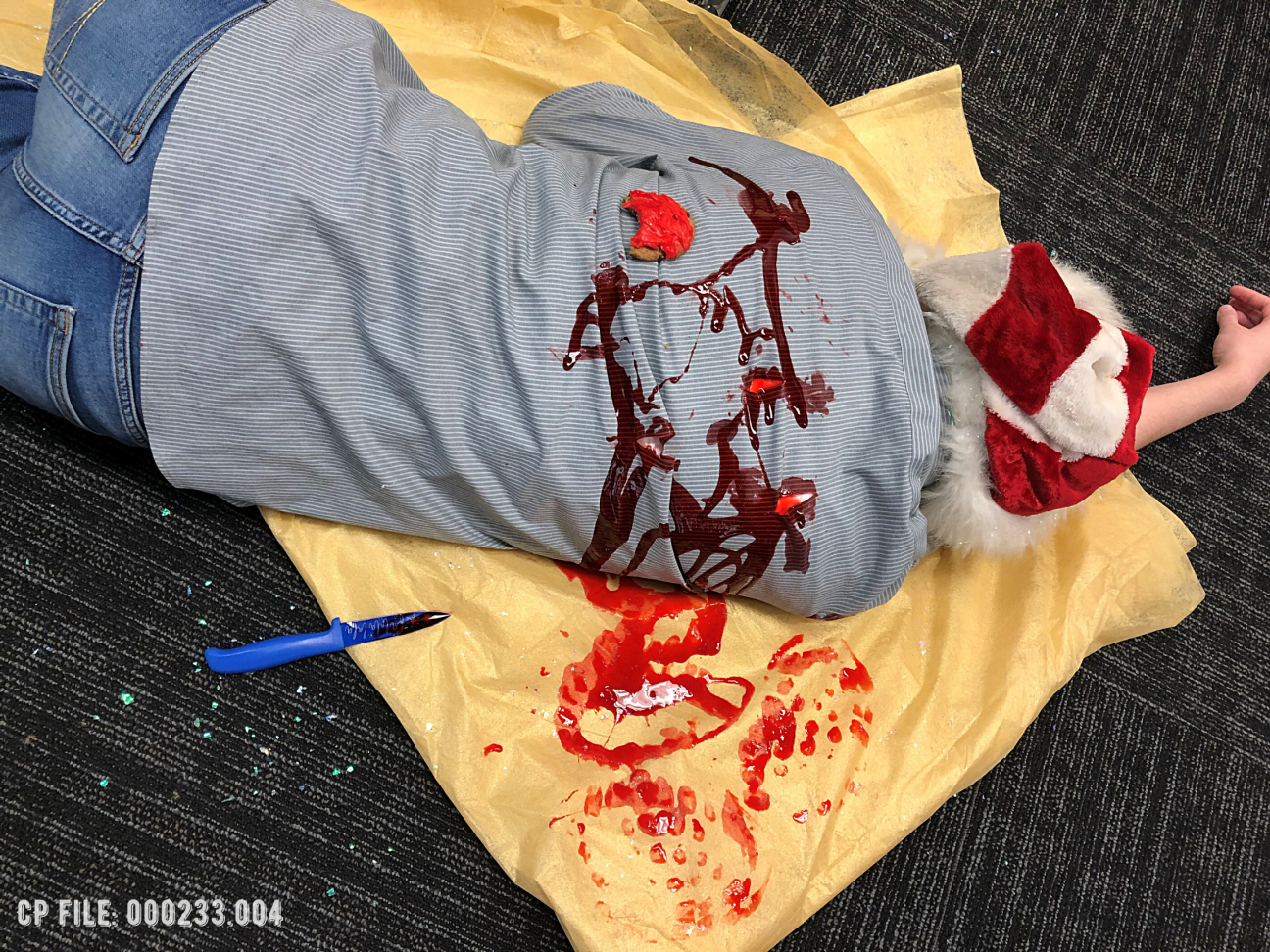 An angled photo of a dead body on top of a bloody tablecloth