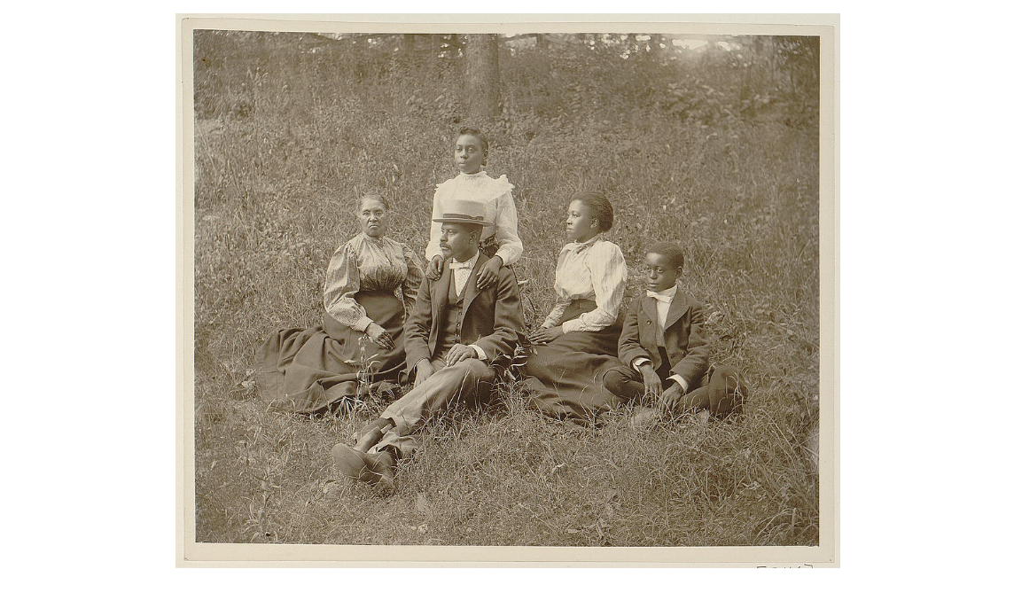 African American family posed for portrait seated on lawn