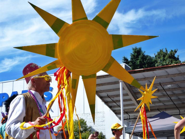 A man walks in the Fremont Summer Solstice Parade with a decorative sun.