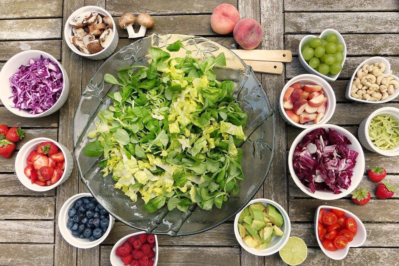 A top down view of a selection of fruits and vegetables in circle and heart shaped containers.