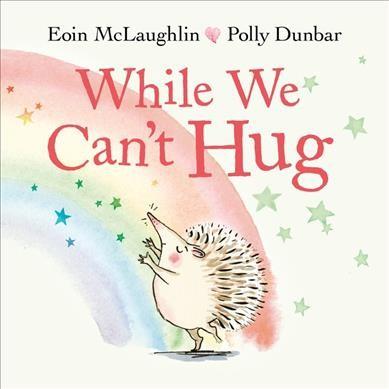 The cover of "While We Can't Hug" by Eoin McLaughlin. The title is at the top in red, above a cartoon drawing of a hedgehog reaching out to their left, with a watercolor rainbow in the background. They are surrounded by colorful stars.