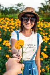 "Man gifting a marigold flower to girl on a marigold field. Man hand with yellow flower." by Artem Beliaikin is marked with CC0 1.0